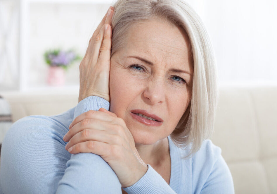 Tinnitus. Closeup up side profile sick female having ear pain touching her painful head. Concept photo with indicating location of the pain. Health care concept